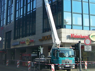 LKW-Arbeitsbühne an einer Geschäftsfassade, der Gehweg ist abgesperrt